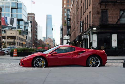 A luxurious red Ferrari sports car parked in urban New York City against a backdrop of modern and vintage buildings.