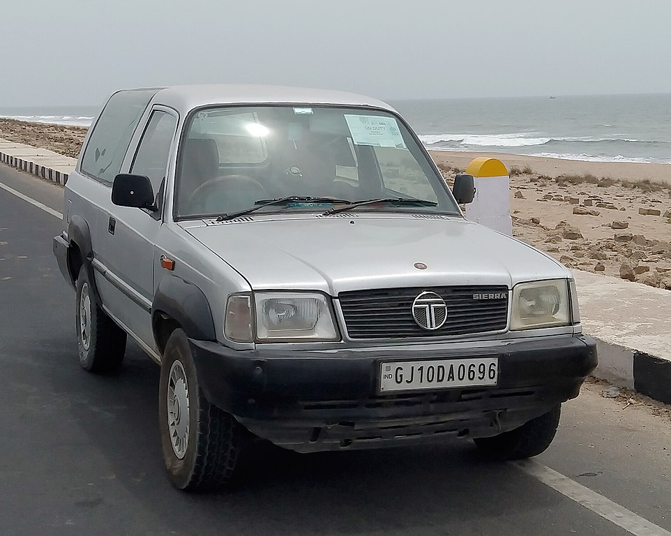 1991 Tata Sierra – A pioneering mid-size SUV from Tata Motors, featuring a 2.0L 483 DL engine, 5-speed manual transmission, and a distinctive 3-door design with large alpine windows. Known for its rugged yet stylish look, rear-mounted spare wheel, and unique front-end resembling the Telcoline pickup. Specifications include a 2,400 mm wheelbase, 4,400 mm length, and a bold presence on the road