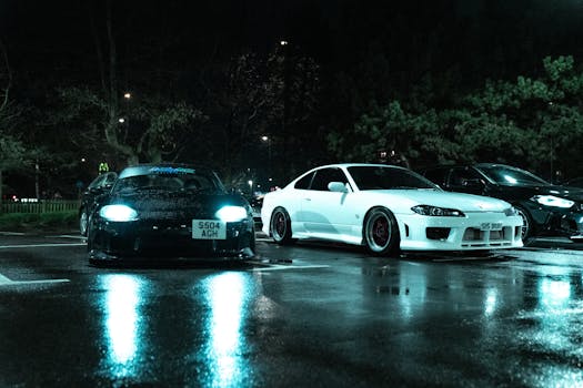 Two Japanese sports cars parked in a wet urban lot at night, with a moody atmosphere.