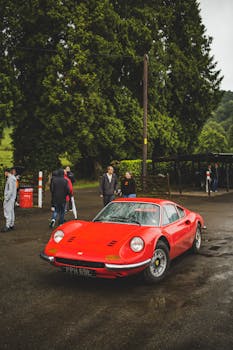Classic red sports car parked outdoors with people around.