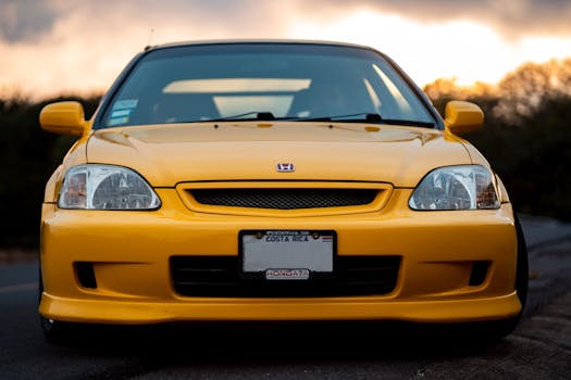 Front view of a striking yellow Honda Civic EK9 on a road during sunset.