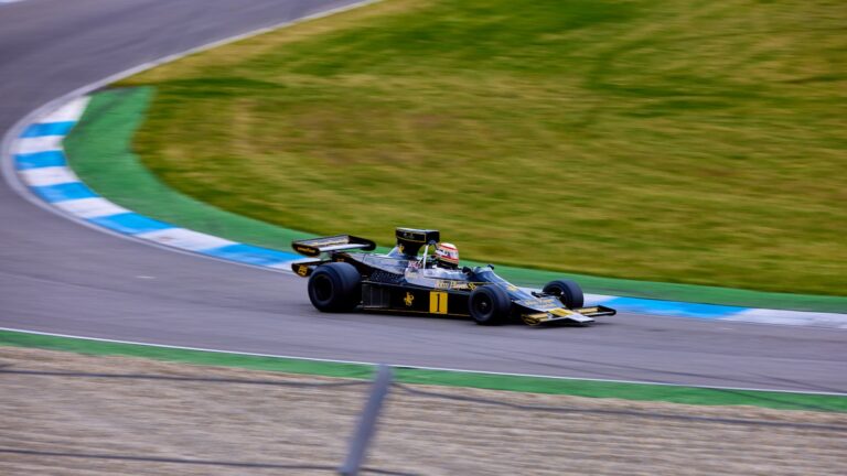 Vintage race car in action on Hockenheim track, showcasing speed and classic design.