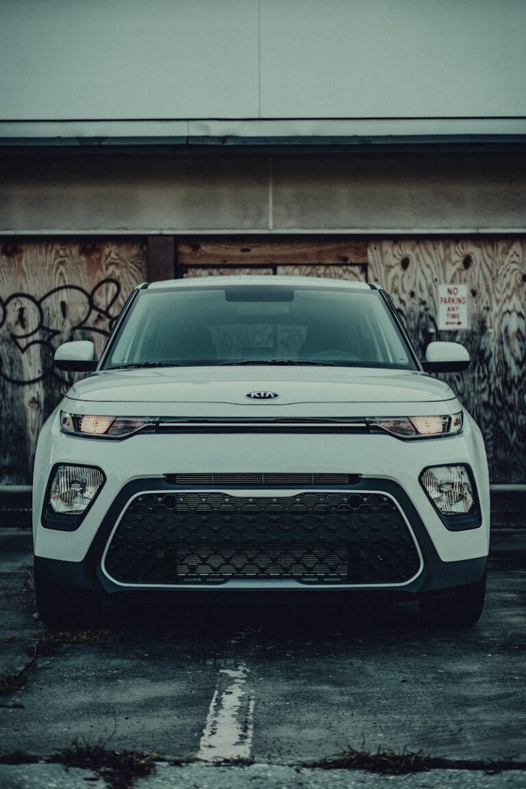 A Kia Soul parked in a gritty urban setting, featuring a striking front view against a graffitied wall.