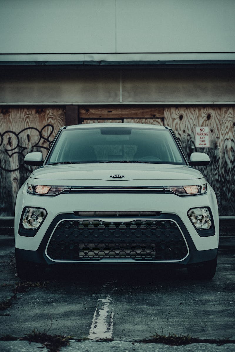 A Kia Soul parked in a gritty urban setting, featuring a striking front view against a graffitied wall.