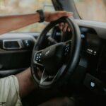 A person driving a modern car, focusing on hands and steering wheel.