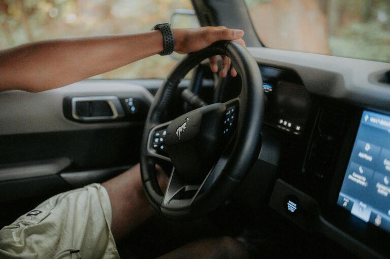 A person driving a modern car, focusing on hands and steering wheel.