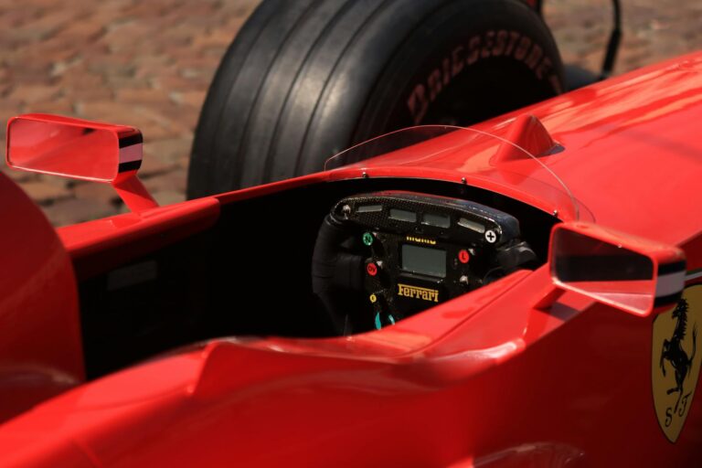 Dynamic close-up view of a red formula one racing car cockpit, showcasing the steering wheel and controls.