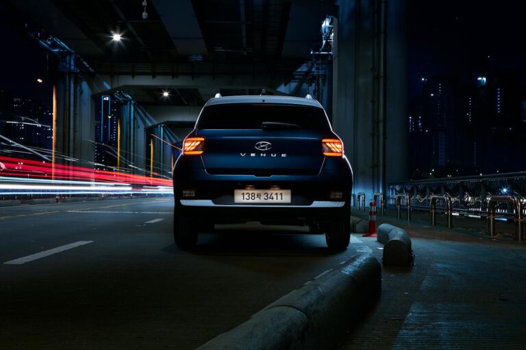 A Hyundai Venue SUV under a city bridge in Seoul at night with striking light trails.