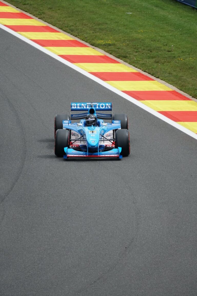 Blue Benetton Formula 1 car speeding on a colorful race track, capturing the thrill of motorsport.