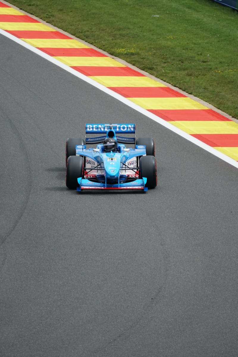 Blue Benetton Formula 1 car speeding on a colorful race track, capturing the thrill of motorsport.
