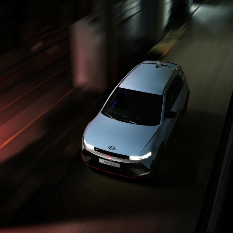 High-angle view of a Hyundai Ioniq 5 electric car speeding on a city street at night.