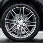 Car tires and Detailed shot of a sleek car wheel and rim on a black vehicle, showcasing automotive design.