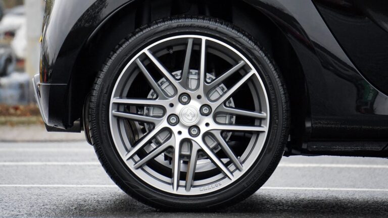 Car tires and Detailed shot of a sleek car wheel and rim on a black vehicle, showcasing automotive design.