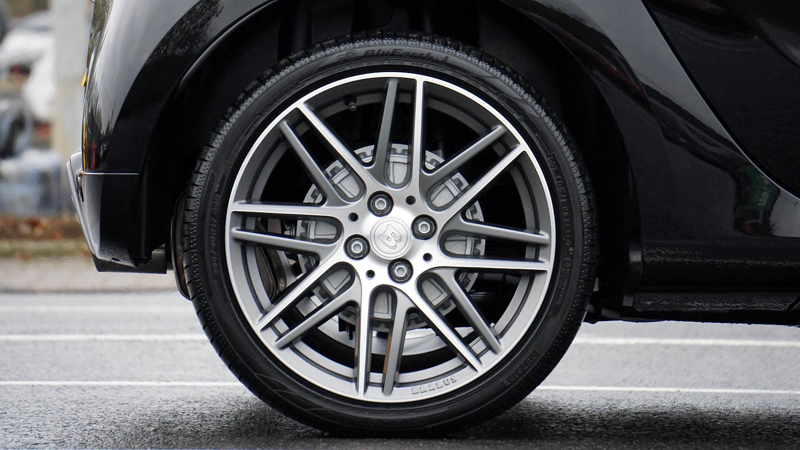 Car tires and Detailed shot of a sleek car wheel and rim on a black vehicle, showcasing automotive design.