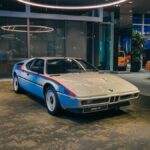 Classic BMW M1 showcased in a modern indoor exhibition, captured with artistic lighting.