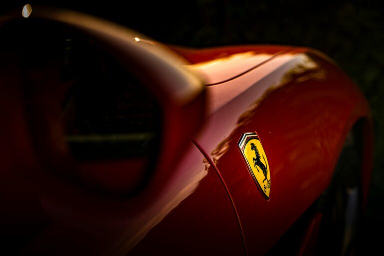 Red luxury sports car with a focus on its emblem and sleek design, perfect for automotive enthusiasts.