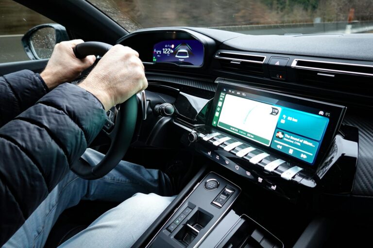 A detailed view of a car's interior with hands on the steering wheel, showcasing modern technology.