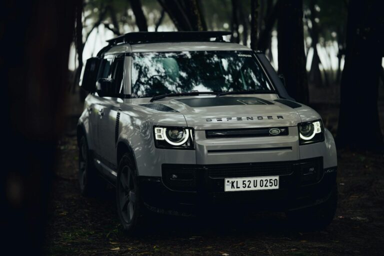 Stylish Land Rover Defender parked in a dark moody Kerala forest.