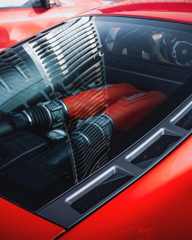 Detailed view of a red sports car engine under a clear cover, reflecting modern design.