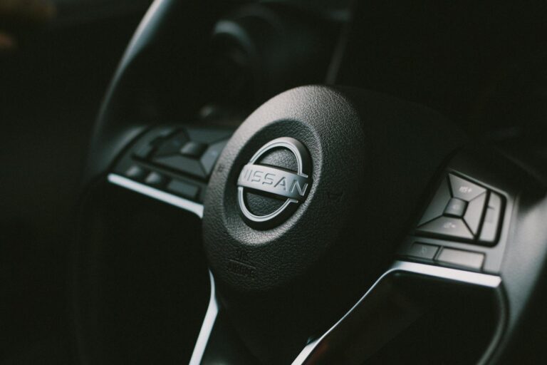 Detailed view of a Nissan steering wheel with visible controls, showcasing automotive design.