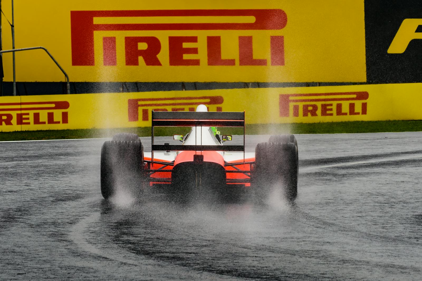 A Formula One car splashes through a wet track under a prominent Pirelli sign.