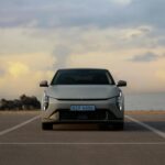 The Kia EV4 parked with the sunset sky and ocean in the background.