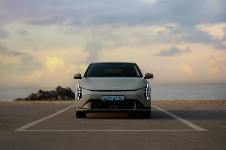 The Kia EV4 parked with the sunset sky and ocean in the background.