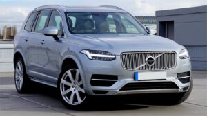 A silver Volvo XC90 SUV parked on an urban rooftop, showcasing the vehicle's sleek design.