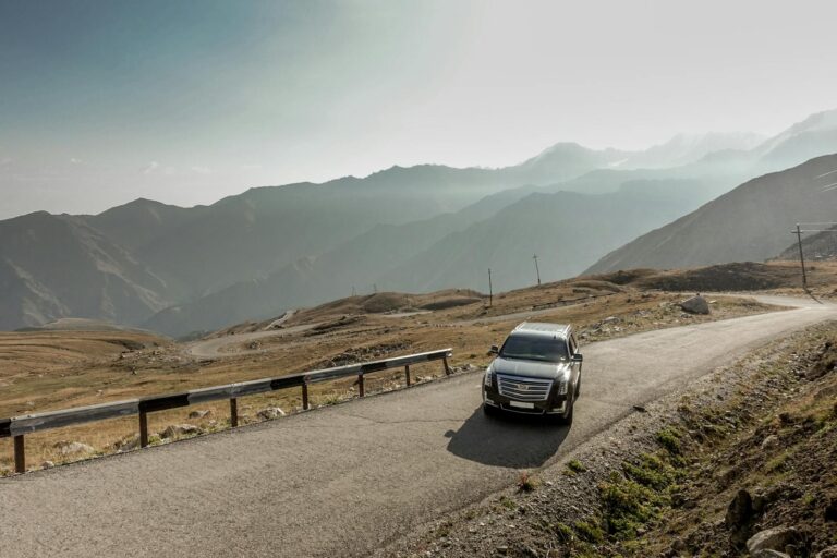 A scenic drive through Almaty's mountain ranges with a parked SUV during the day.