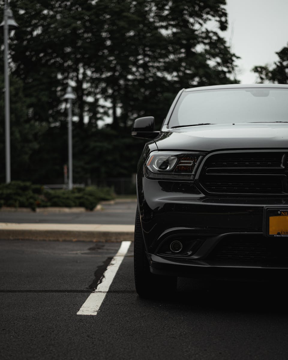 A sleek black SUV parked in an urban lot during the day, featuring a distinctive front grille.