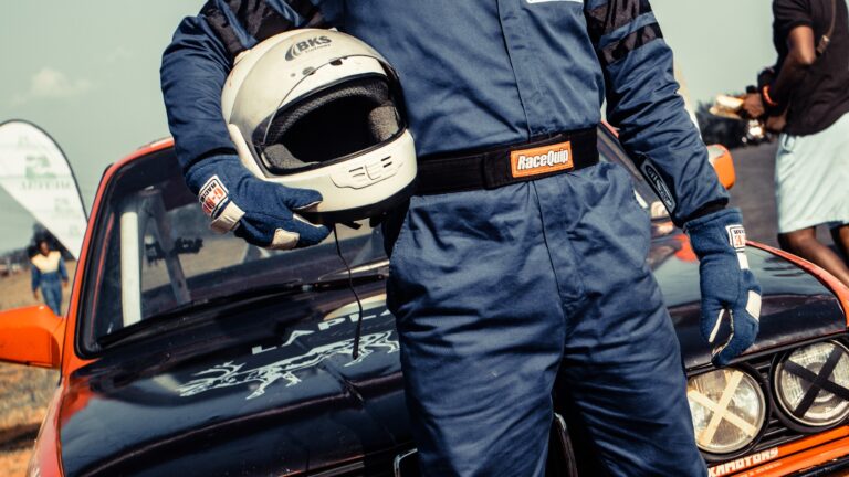 man in blue racing suit standing in front of blue coupe