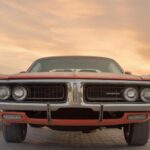Front view of a classic Dodge muscle car under a vibrant sunset in Sharjah, UAE.