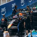 Formula One pit crew servicing the racing car during a pit stop at a wet track.
